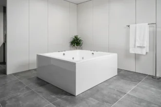 Baignoire rectangulaire balnéo moderne encastrée dans une salle de bain contemporaine avec carrelage gris grand format