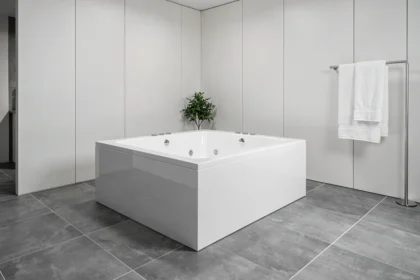 Baignoire rectangulaire balnéo moderne encastrée dans une salle de bain contemporaine avec carrelage gris grand format